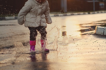 Child jumping in the muddy puddle. closeup of bootsの写真素材