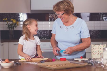 little girl and grandmother roll out the doughの写真素材