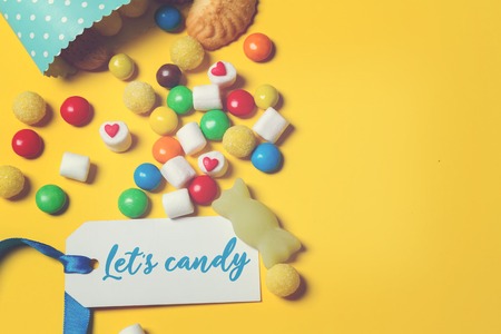 Mixed colorful candies scattering of sweets on yellowの写真素材