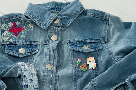 Close up view of denim jeans jacket with cool graphic pins