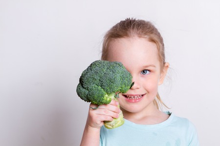 little girl beautiful having fun with broccoliの写真素材