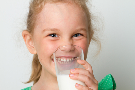 Cute girl holding glass of milkの写真素材