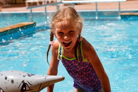 girl swimming in a pool smiling and having a happy dayの写真素材
