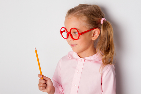 Education and inspiration. Little girl having idea, raising pencil in funny attention gestureの写真素材