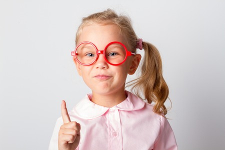 Closeup portrait of beautiful young smiling girl, pointing with index finger upwardsの写真素材