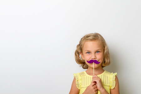 Free time for fun. Close up portrait small girl with fake mustache with plumpの写真素材