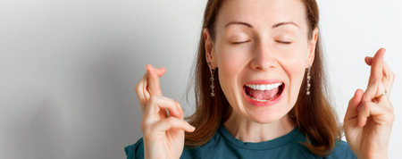 Young woman crossing her fingers and wishing for good luck