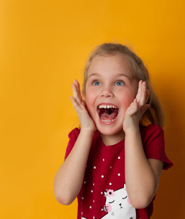 Image of excited screaming cute little standing isolated over yellow background. Looking away...