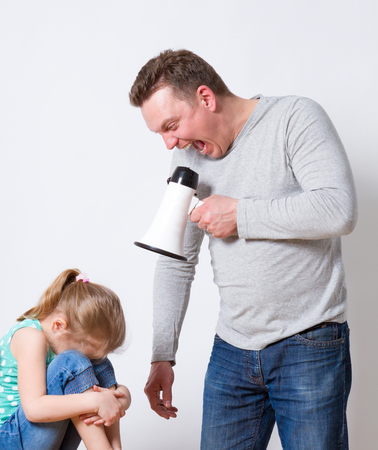 Father with megaphone screaming at son standing with crossed arms and looking away, family problems conceptの写真素材