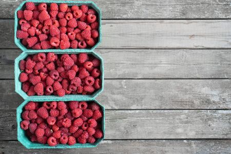 Fresh red raspberries in craft stalls, containers. on a wooden rustic old background. Top view of ripe berries. Autumn harvest.の写真素材