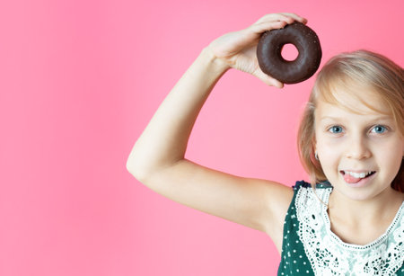 Funny happy girl with donut donuts on a pink background. Close-up portrait with a funny teen girl with a donut. Makes mouse ears out of sweetnessの写真素材