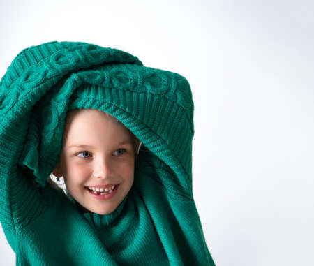 Playful little girl wearing knitted green sweater that is too big for her and raising hands in long sleeves above head. Happy childhood, facial expression, cute kids. Close up shot isolated on white.の写真素材