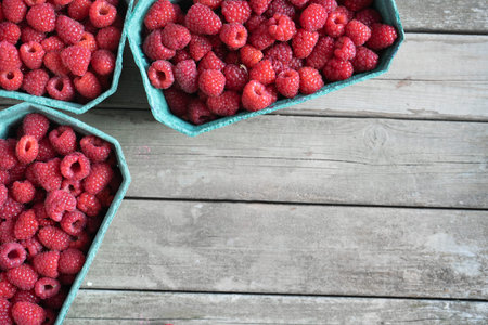 Fresh red raspberries in craft stalls, containers. on  wooden