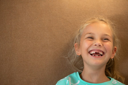portrait of a cheerful girl playing on the floor in the childrens room, she cheerfully smiles at the...