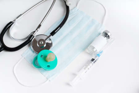 Medical mask, stethoscope, syringe with medicine and pacifier on a light background. Vaccinations for children.の写真素材