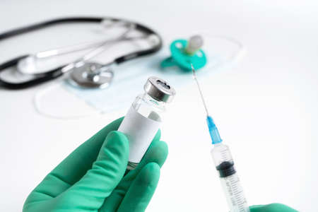 hand of the medical staff is holding a vial with a medicine and a disposable syringe, getting ready with an injection to a child.の写真素材