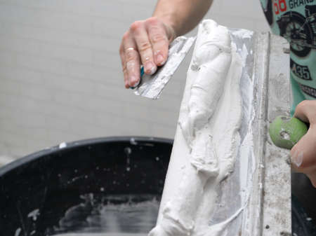 The process of applying layer of putty trowel for light plaster wallsの写真素材