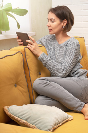 Young woman reading e-book on the couch