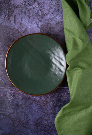 Empty green ceramic plate with a green linen napkin on a blue table. View from above.の写真素材