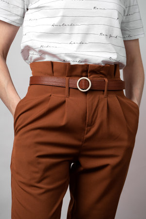 woman in a white T-shirt and brown chinos with a leather belt. Casual wear for cozy weather. Contemporary urban fashion.の写真素材