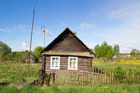 Wooden house on the edge of the village in summerの写真素材