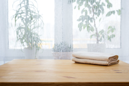 Table with a towel and indoor flowers against the windowの写真素材