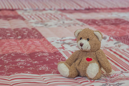 Toy bear on a pink and white bedspread at hotel