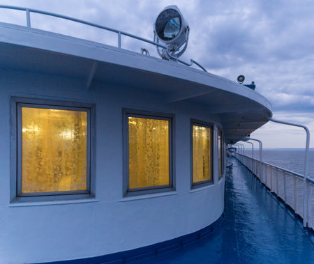 Deck of a passenger ship with luminous windows at dusk