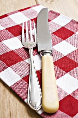 Antique knife and fork on a red and white clothの写真素材