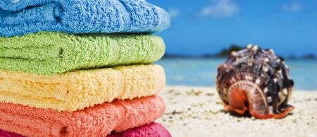 Colorful towels on a white beach with a beautiful sea shellの写真素材