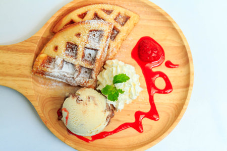 Waffles ice cream and whipped cream served on a wooden tray.の写真素材