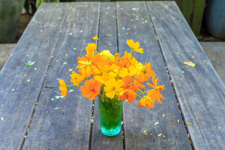 Little yellow star in a water glass on the wooden table in garden.の写真素材