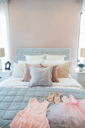 Ballet set and many pillow on a girl bed with bedside lamp in warm light bedroom.のeditorial素材