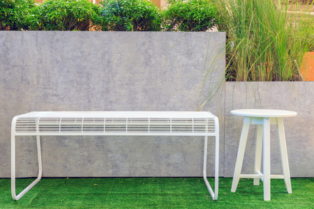 White steel chairs and wooden chairs on artificial grass and clay pots in the Garden held.の写真素材