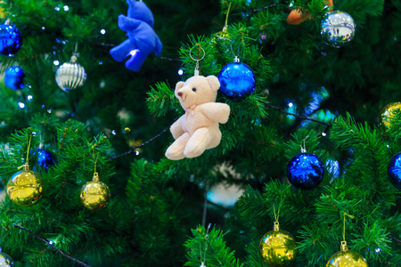 A white bear doll decorated on Christmas tree with colorful hanging ball background.の写真素材