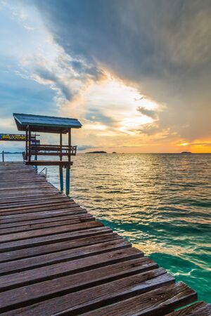 Seascape view with wooden bridge and pavilian on the beach with sea and colorful sky at sunrise.の写真素材