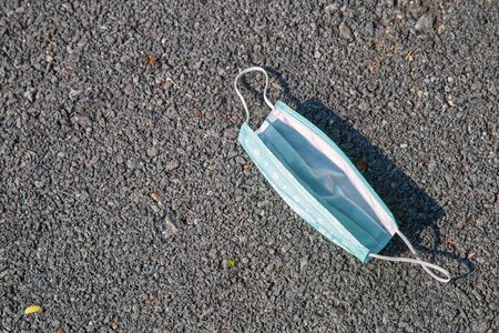 An used light blue face mask drop on the road, The face masks used for the anti-corona virus that were used were left on the floor.の写真素材
