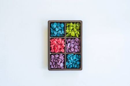 Top view close up A-lua or Allure" Thai handmade candy in rown plastic box on white floor blank for copy space. A-lua or Allure is traditional Thai desserts sweet and delicious.の写真素材