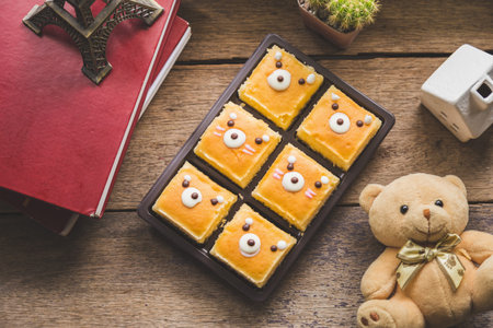 Hight angle view group of butter cake in a black plastic pack next to a books with a cactus and...