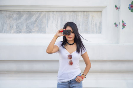 Portrait beautiful Asian woman in a white T-shirt looking at a camera at the Wat Arun temple while...
