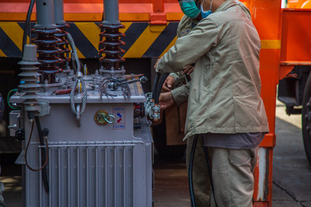 Nonthaburi, Thailand- May 19, 2021: Electrical wireman are  installing cable to transformer for a light poleのeditorial素材