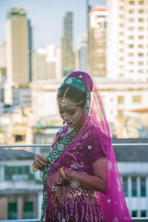 Portrait charming Asian woman wearing a traditional saree looking at down while touching her cloth with urban building background.の写真素材