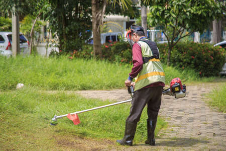 An old Asian gardener's man post with lawnmowers before working in the garden.の写真素材