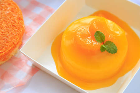 An orange cake with orange topping and pepermint on a white table.の写真素材