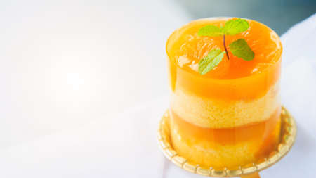 An orange cake with orange topping and pepermint on a white table.の写真素材