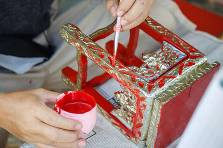 Close up A man's hand holding a brush is painting red on the altar tableの写真素材