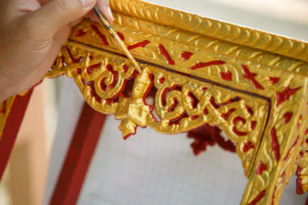 Close up A man's hand holding a brush is painting golden on the altar tableの写真素材