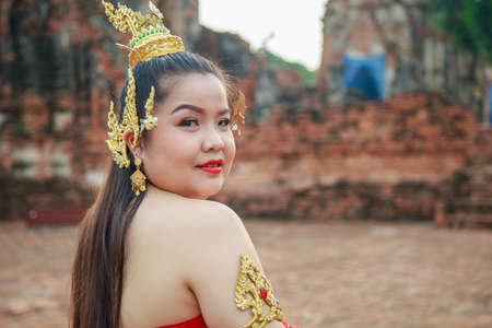 Asian woman in a pink dress cross her arms wearing a face mask with an old brick wall background.の写真素材