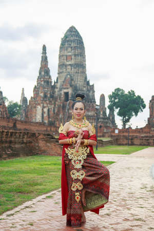 Asia woman wearing traditional Thai dress, she is posting with ancient ruin temple background.の写真素材