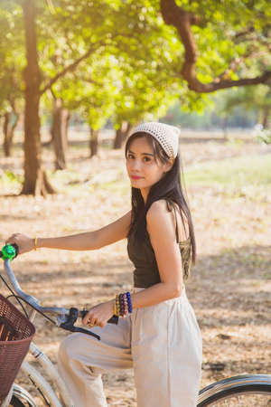 Portrait Asian woman in a green singlet sitting on a bicycle on a lawn with nature background in a parkの写真素材
